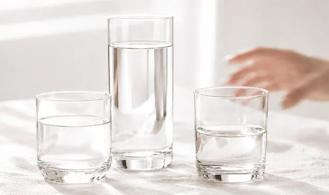 Three glasses of fresh water in different sizes on a bright table